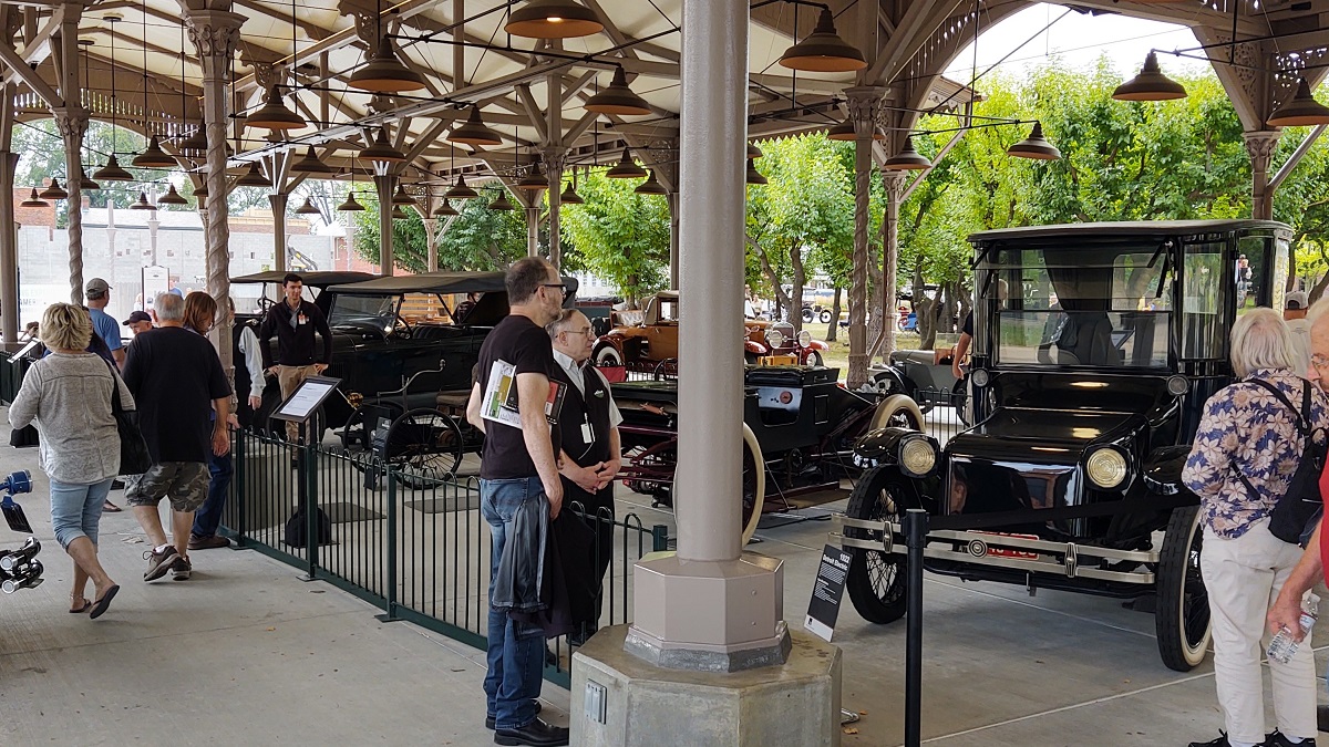 Luxury vehicles displayed in Detroit Central Market during Old Car Festival 2022 Spectators look at a row of cars displayed behind barriers in an open, shed-like building