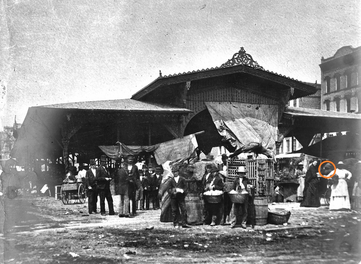 Large open-sided building with vendors selling wares to people outside