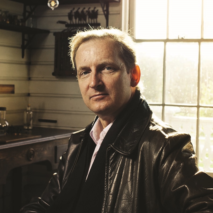 Marc Greuther Portrait of man in black leather jacket sitting in workshop with window behind him