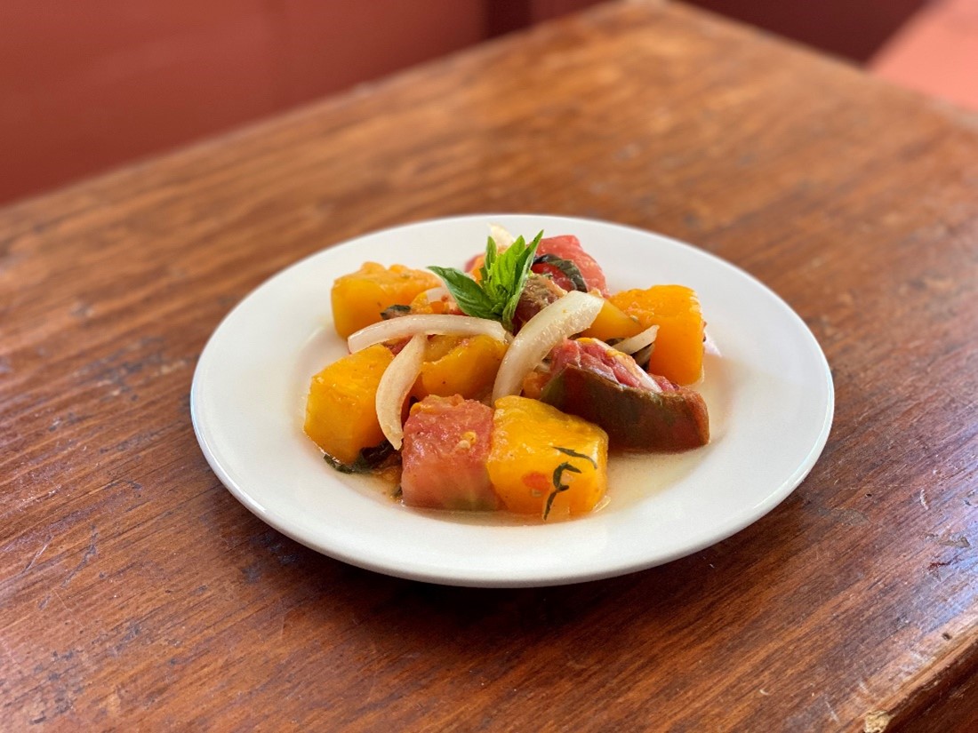 Heirloom Tomato Salad with White Wine Vinaigrette A plate holds a salad of large chunks of multicolored tomatoes in dressing, with a sprig of basil in the middle