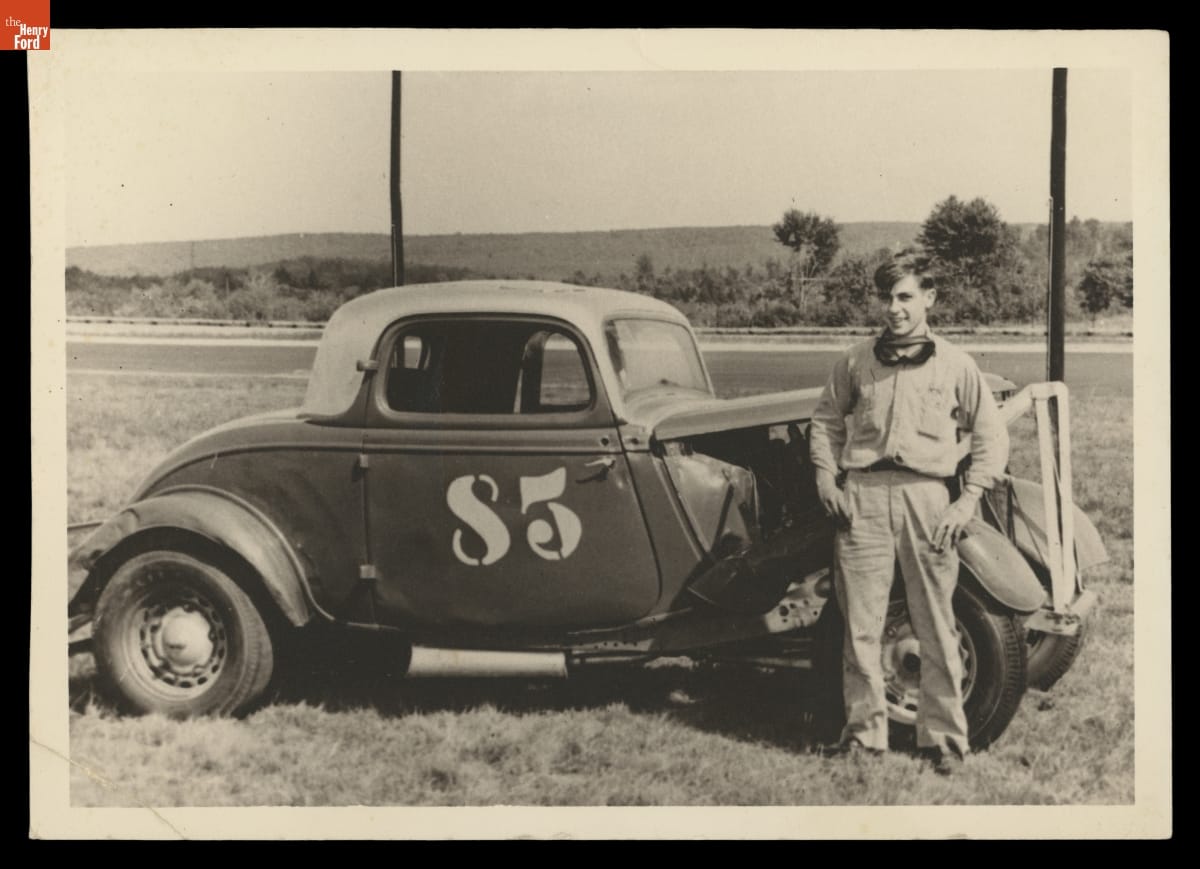 Basil "Jug" Menard Posing with a Modified Ford Coupe Race Car. Taunton, Massachusetts, circa 1946 Boy stands next to car in field
