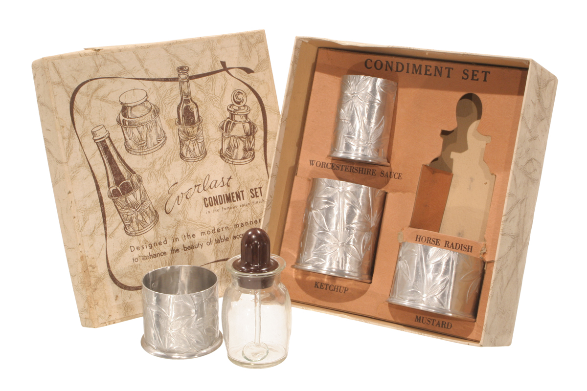 Everlast "Bali Bamboo" Condiment Set, 1948-1959 Box containing silver canisters; additional silver canister and glass in front; box lid with text and drawings of canisters nearby