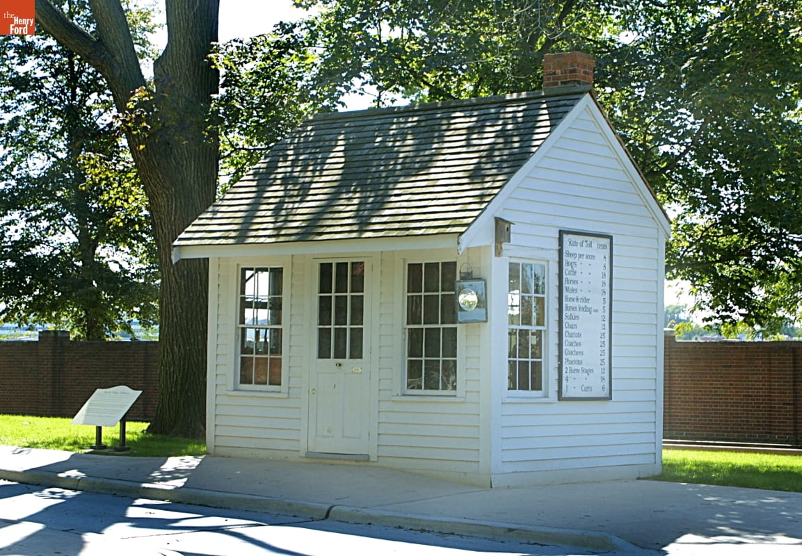 Rocks Village Toll House Small white wooden building with sign on side, shaded by a tree