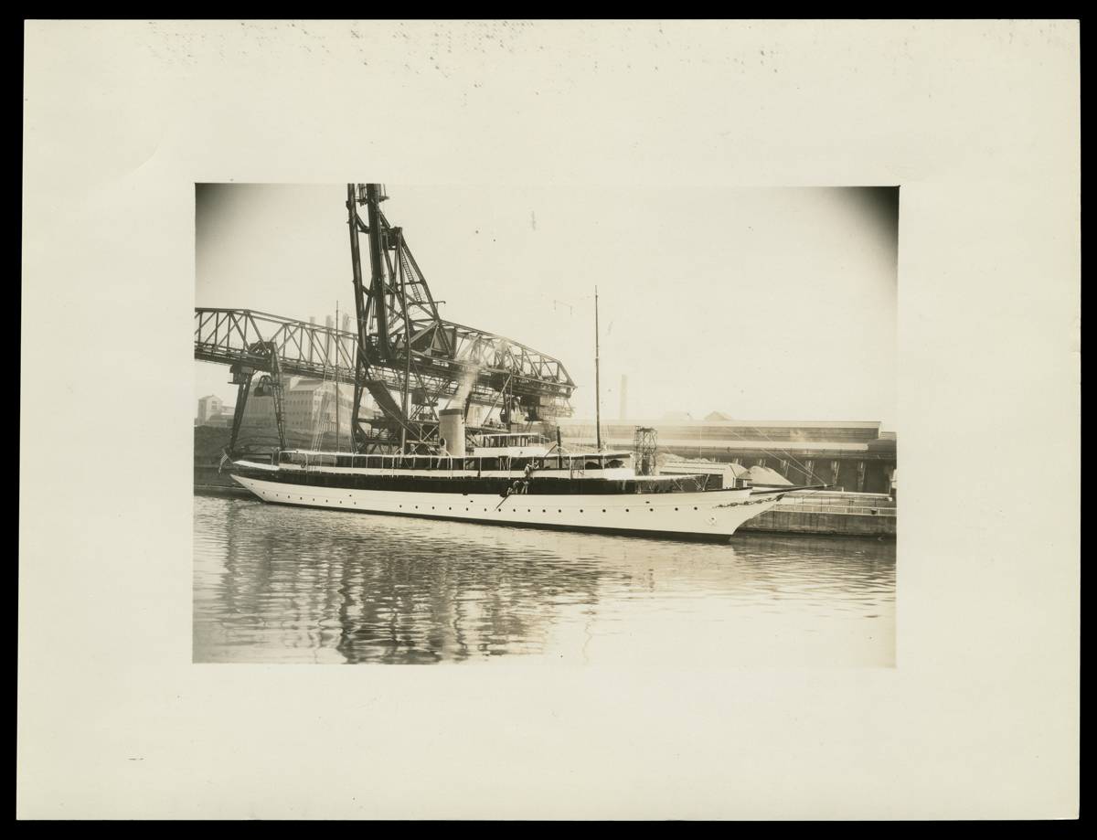 Henry Ford's Yacht "Sialia" Docked at Ford Rouge Plant, Dearborn, Michigan, 1927 Long boat docked next to an industrial crane or craneway
