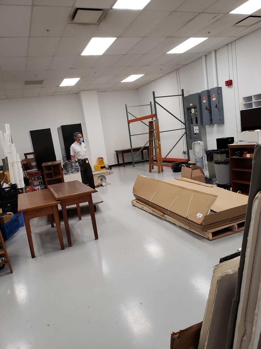 Man stands among furniture and supplies in large open room