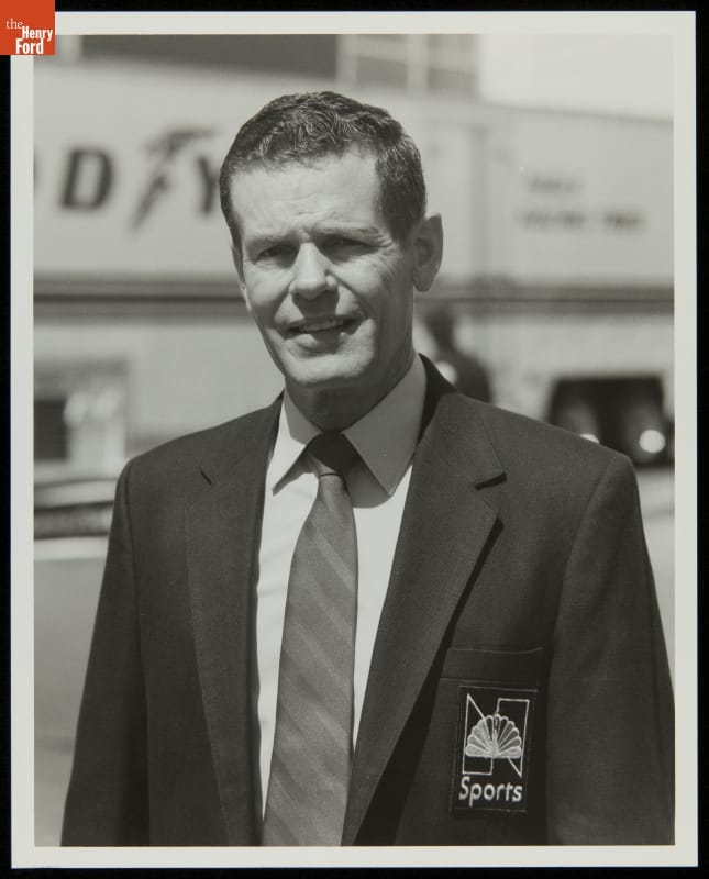 Bobby Unser, NBC Sports, 1985 Man in suit and tie with NBC peacock logo on pocket looks at camera