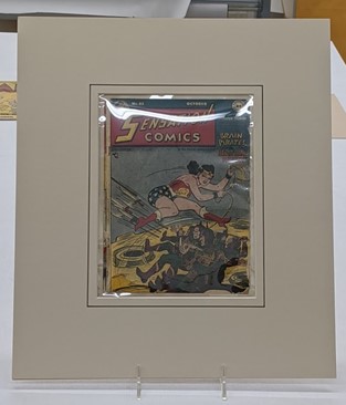 Plastic-covered "Sensation Comics" comic book in mat