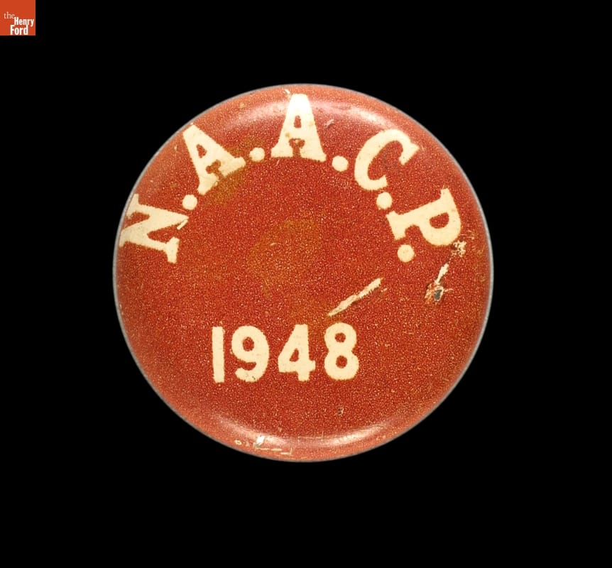 Round red button on black background with text "N.A.A.C.P 1948"