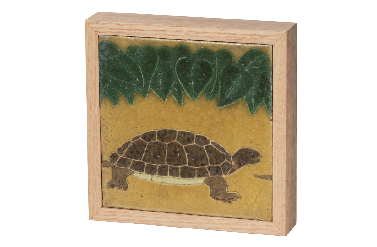 Tile of turtle on yellow background under green leaves