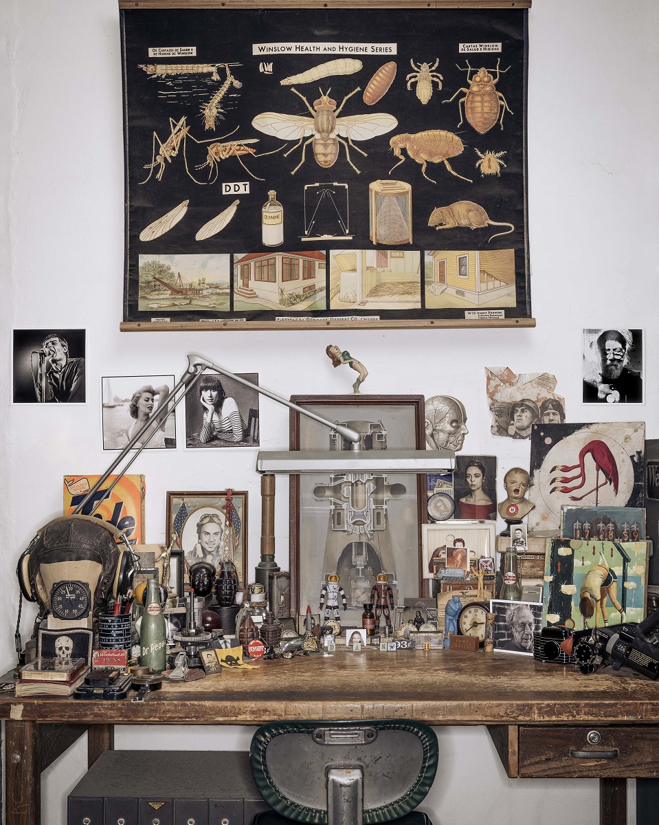 Dan Winters' desk Desk littered with models, framed images, knickknacks, and more, with even more items hanging on wall above desk
