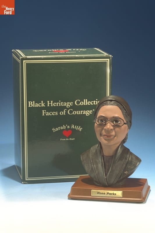 Commemorative Bust of Rosa Parks, 1995 Small statue of woman's face and partial torso on base with text; sitting next to green box with text