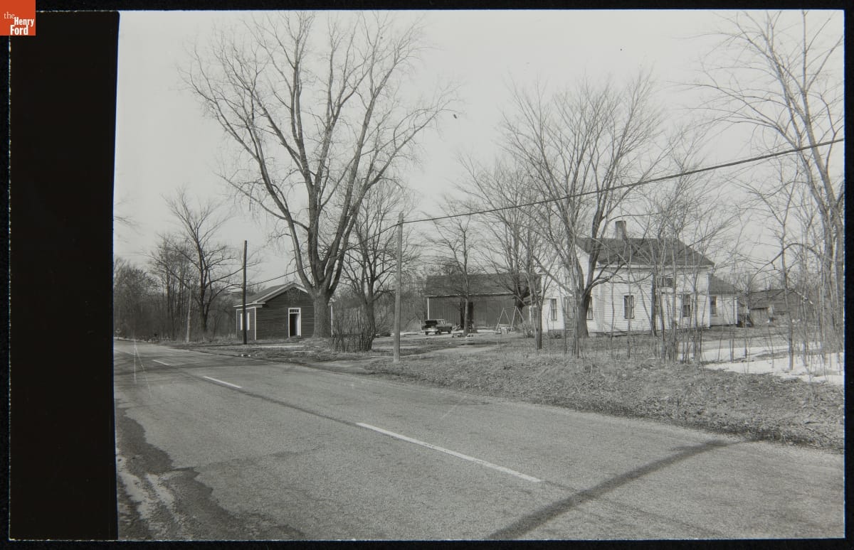 Dr. Howard's Farm and Office at its Original Site, Tekonsha, Michigan, March 1956 Black-and-white photo of several wooden buildings by side of two-lane road among trees