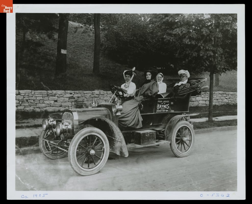 Four Ladies in a Haynes Automobile Traveling From Chicago to New York, circa 1905 Four women in an open automobile with text on door "Four Ladies in a Haynes from Chicago to New York"
