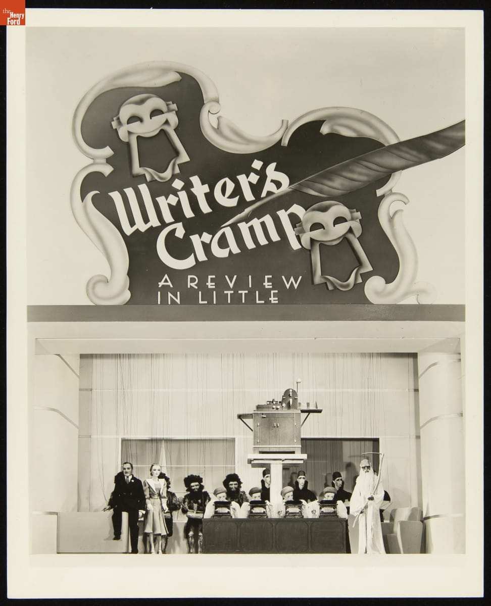 "Writer's Cramp: A Review in Little" Marionette Show at the A.B. Dick Company Exhibit at the New York World's Fair, 1939 Sign with decorative edges, text, and smiling and frowning theater faces above office-themed puppet show