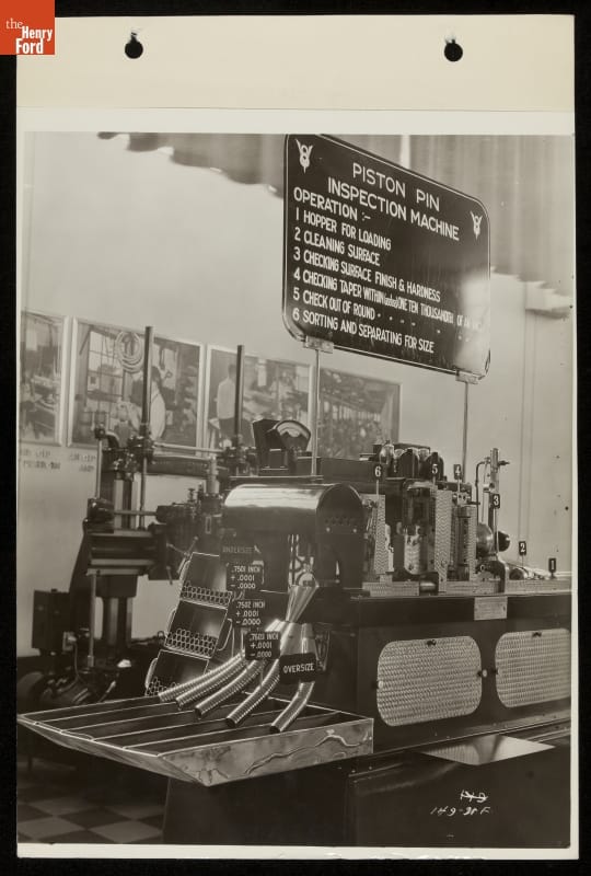 Piston Pin Inspection Machine, Ford Exhibition Building, Century of Progress International Exposition, Chicago, Illinois, 1934 Machine on display under a sign with text, with images along wall behind