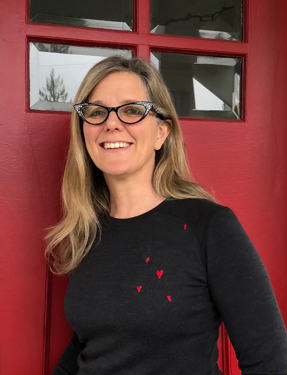 Berene Campbell, North Vancouver, British Columbia, Canada Light-skinned woman with blonde hair and glasses, wearing black sweater with small red hearts, in front of a red door