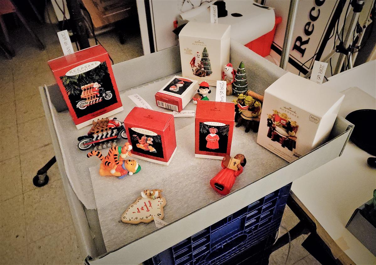 Ornaments with their packages and accession number tags ready for photography Christmas ornaments and boxes in large, flat, open gray box