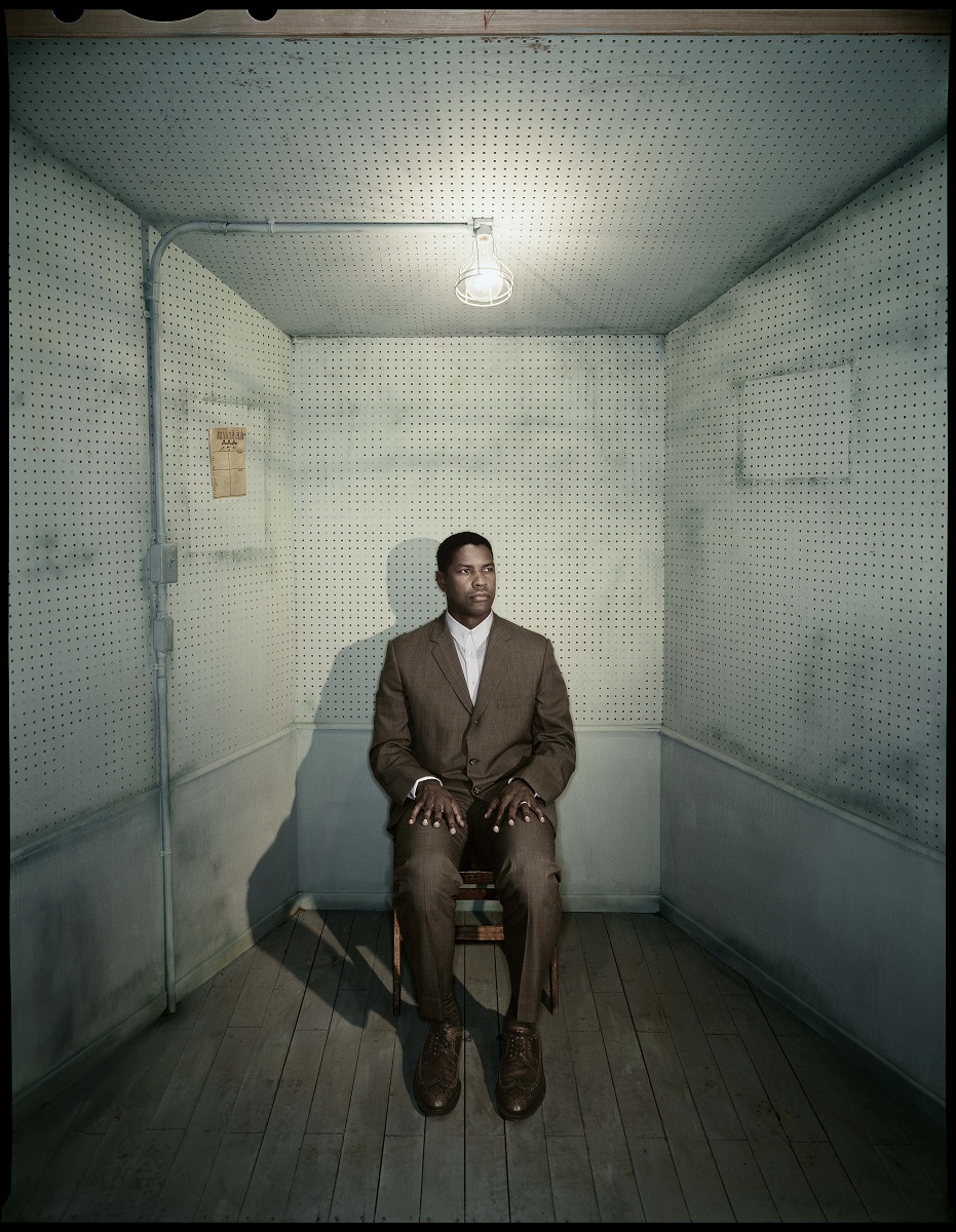 Denzel Washington, photographed by Dan Winters Man in suit sits with hands on thighs in room with skewed perspective