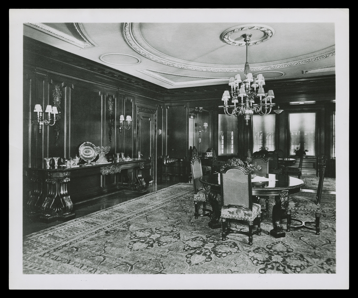 Dining Room at Fair Lane, Home of Clara and Henry Ford, circa 1925 Room interior with round dining table and four chairs, oriental rug, and ornately carved wooden walls and plastered ceiling