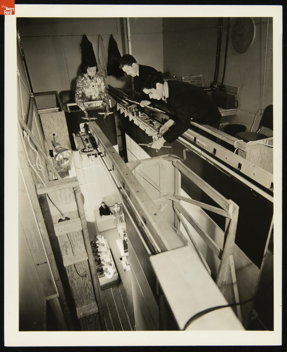 Operating the Marionettes in "Writer's Cramp: A Review in Little" Marionette Show at the A.B. Dick Company Exhibit at the New York World's Fair, 1939 Three people on an elevated balcony or catwalk hold wooden crosspieces supporting puppets below
