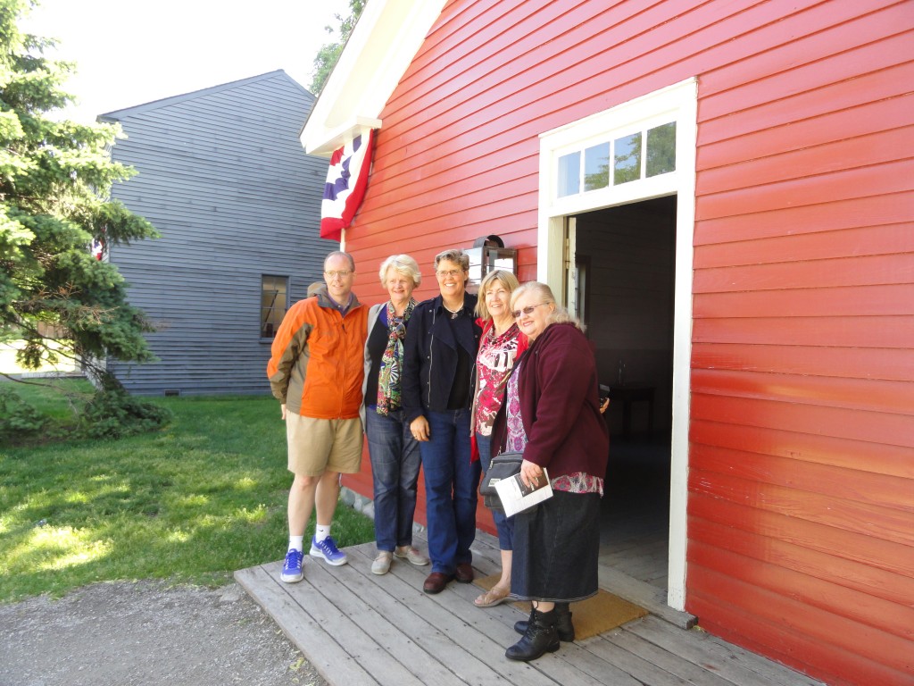 Five descendants of Dr. Howard in front of his office Five people with arms around each other pose for camera in front of a red wooden building