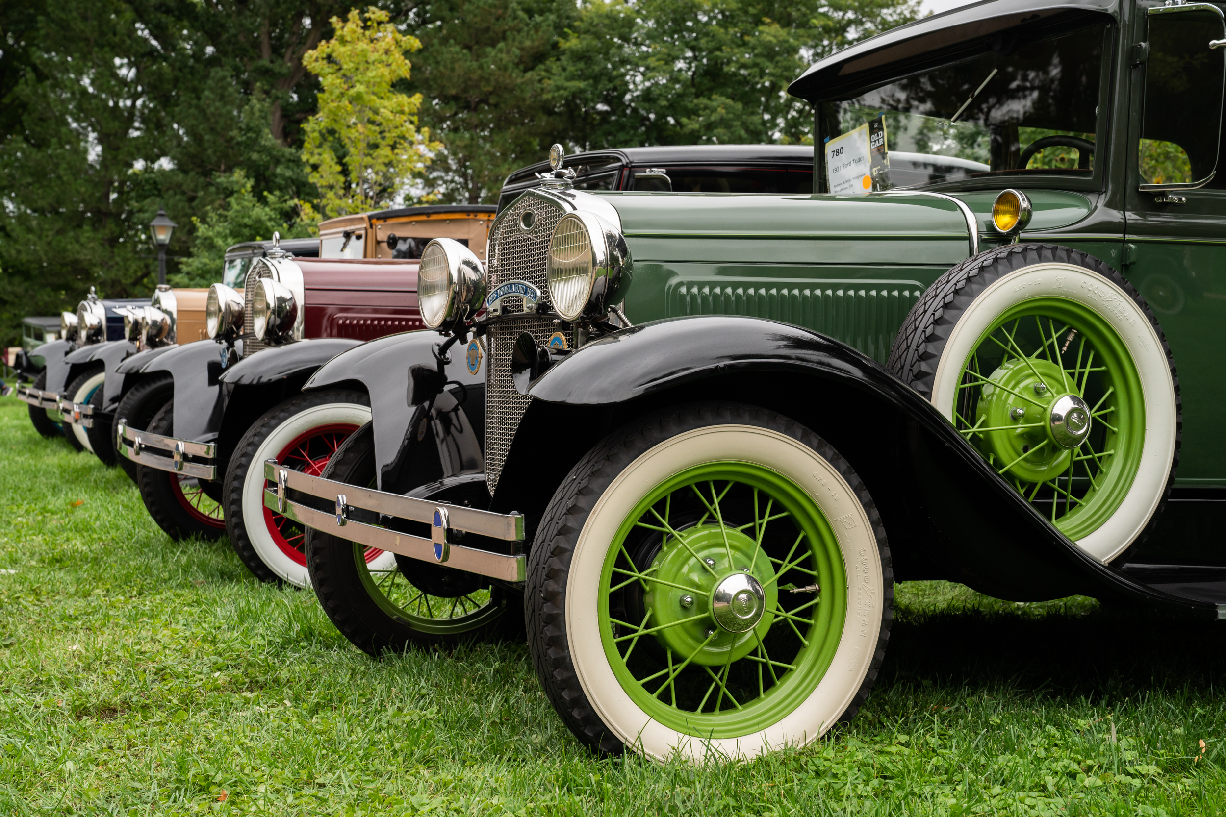 Row of antique vehicles parked on green grass