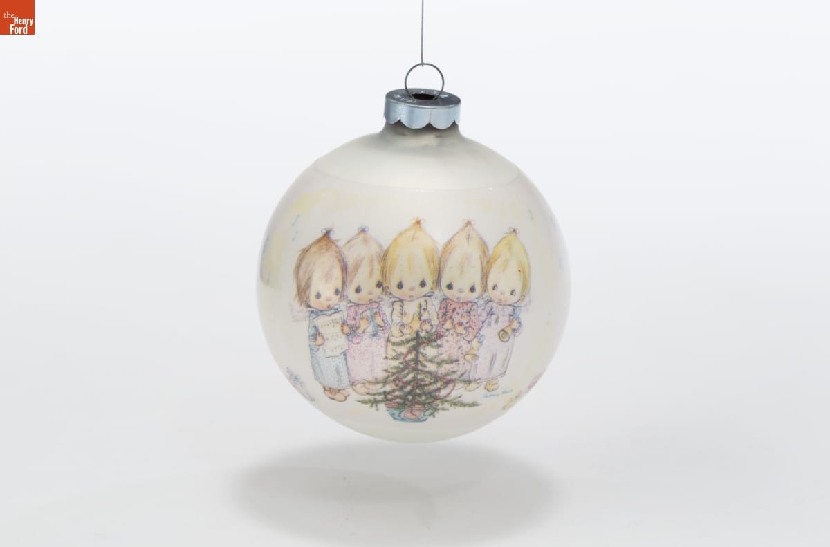 Hallmark "Betsey Clark" Christmas Ornament, 1973 Round white Christmas ornament with image of 5 young children with fine hair holding musical instruments and sheet music around a small Christmas tree