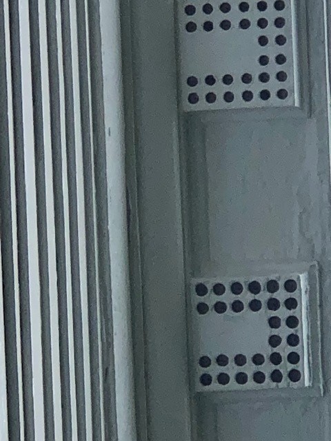 Mutules on the Webster House Architectural elements of white boxes with round holes in a "U" pattern in them