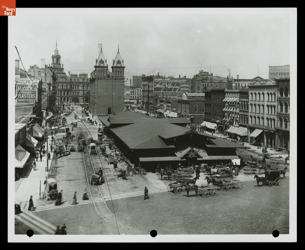 Central Market in Downtown Detroit, Michigan, circa 1890 Long, low building in city square, surrounded by roads and other buildings