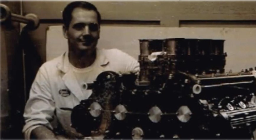 Black-and-white photo of man with a car engine