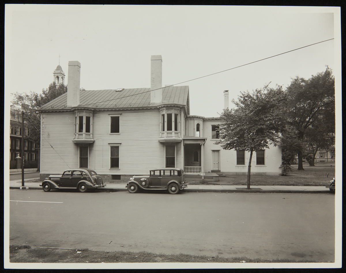 Large house with two cars parked on street by it