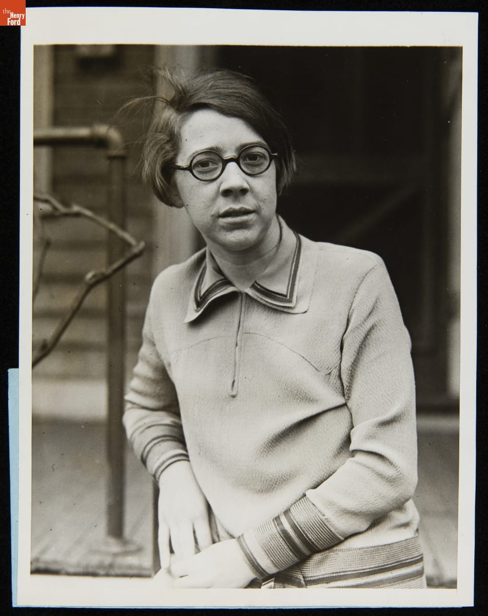 Woman with bob wearing round glasses in front of a porch