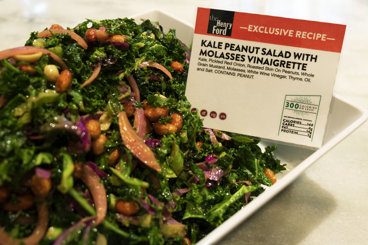 Kale, Roasted Peanut, and Pickled Red Onion Salad with Molasses Vinaigrette White ceramic dish containing a colorful salad and label with text, sitting on white and gray marble counter