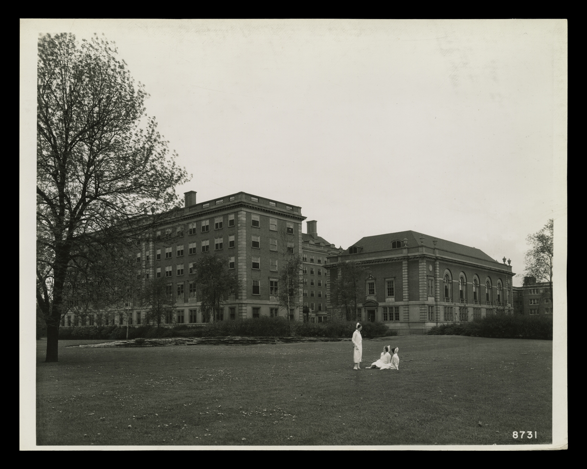 Grounds of Henry Ford Hospital and Clara Ford Nurses Home, Detroit, Michigan, circa 1930 Large five (?) story brick building, with three people in nurses' outfits on the lawn in front