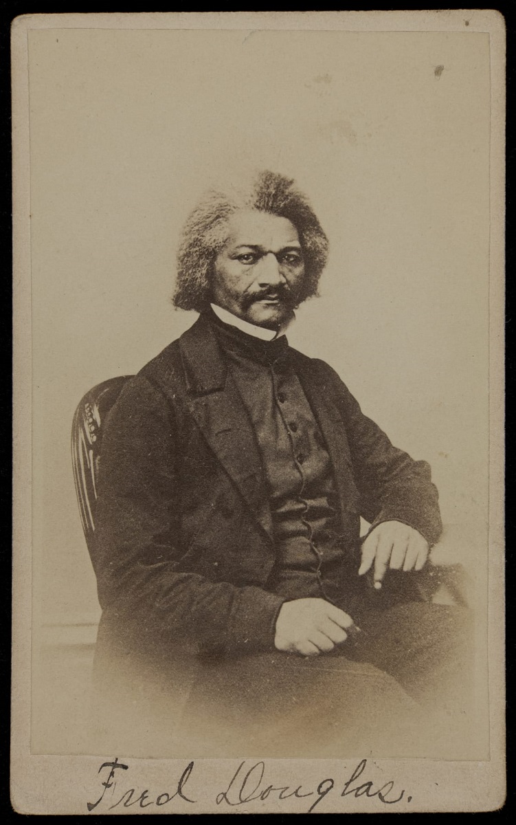 Portrait of seated Black man, wearing suit with high collar, with mustache and bushy salt-and-pepper hair