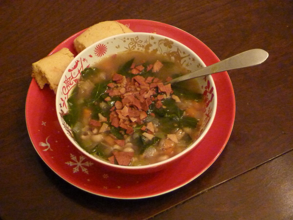 Vegetarian hoppin’ john soup Bowl filled with soup and topped with vegetarian bacon; cornbread on side