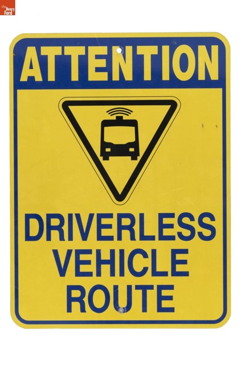 "Attention Driverless Vehicle Route" Sign, 2018 Yellow sign with text "ATTENTION DRIVERLESS VEHICLE ROUTE" and icon of a van in upside-down triangle