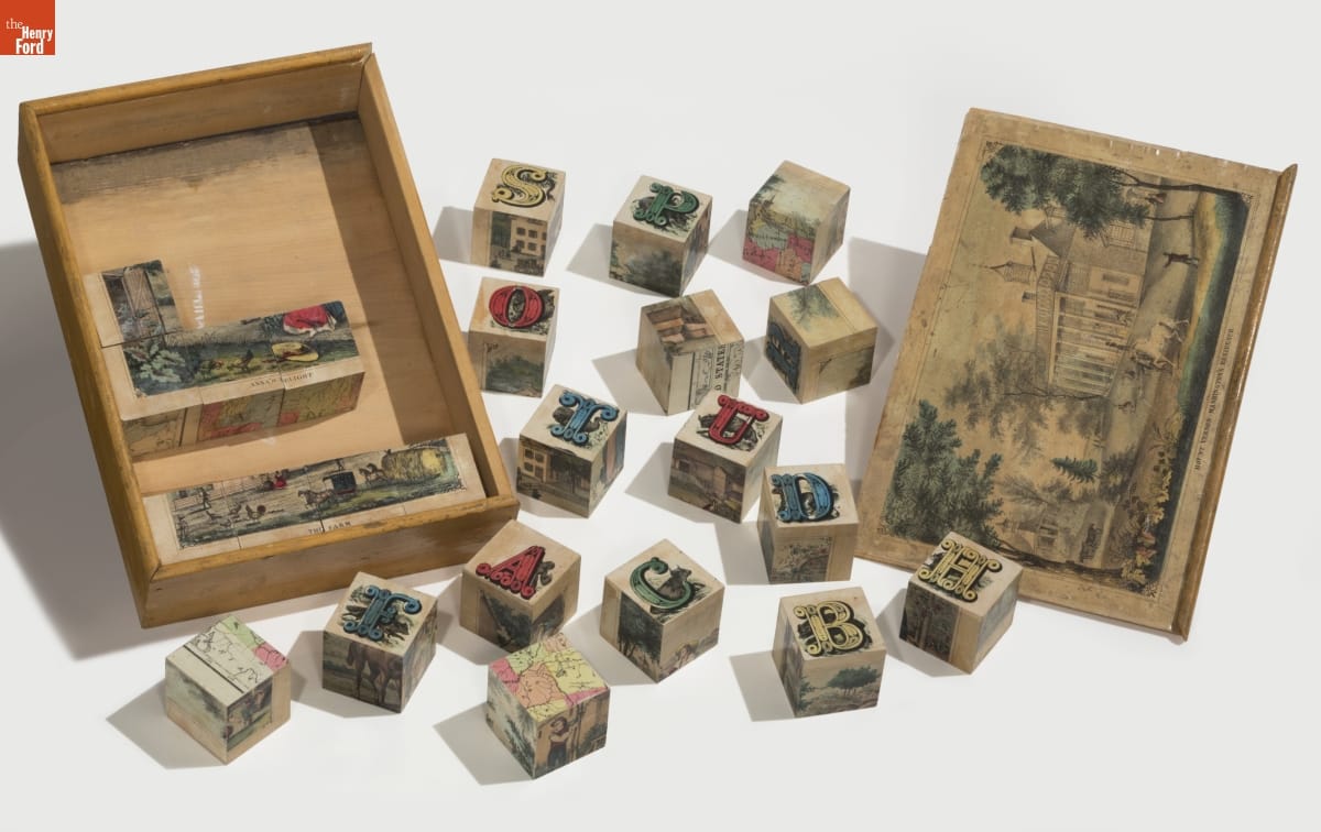Picture Puzzle, 1858-1863 Wooden box with some blocks in it and other blocks scattered around; top of box contains image of house and grounds