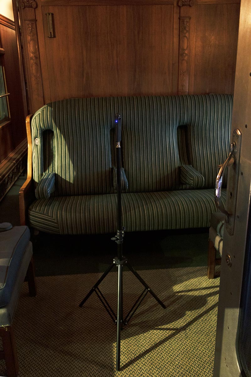 Ricoh Theta camera, mounted on a stand, ready to capture the interior of the Fair Lane railcar lounge Small camera on a tripod in a room in front of striped upholstered seating