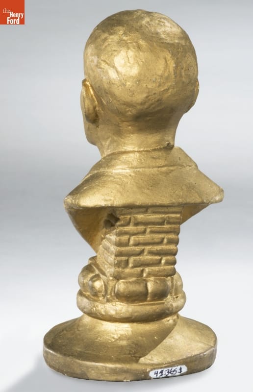 Bust of George Washington Carver, circa 1941 / back Back of gold sculpture of man's head and partial torso on a base designed to look like bricks