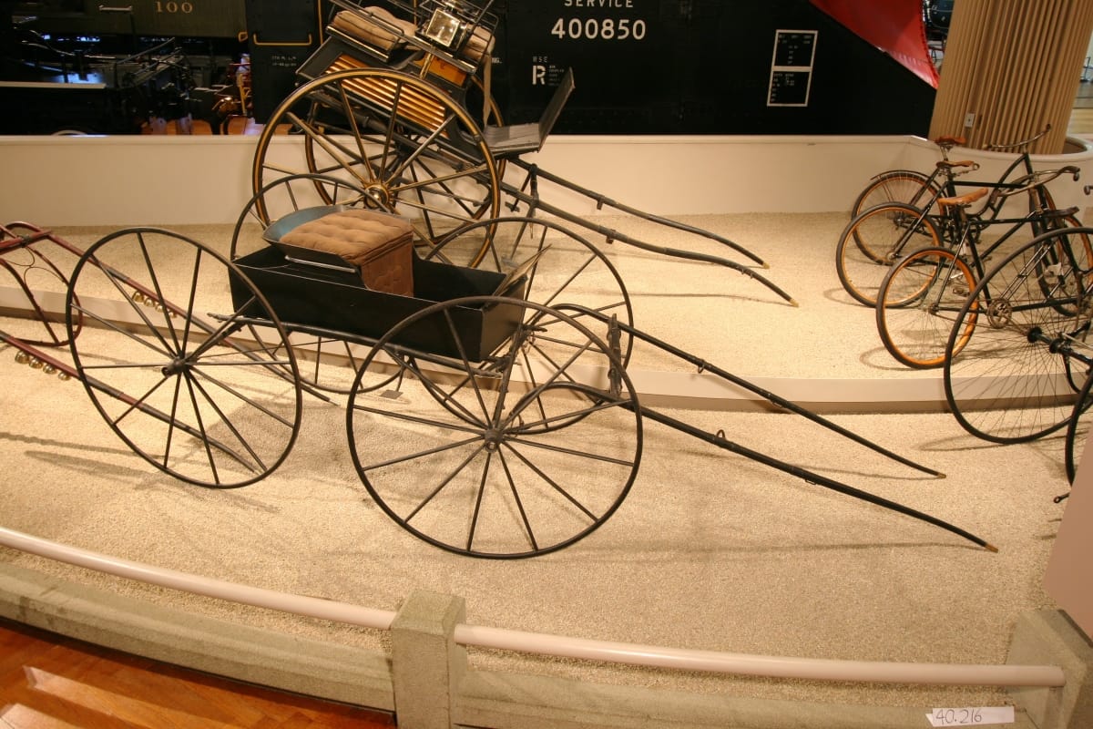 Runabout, 1876 Minimal carriage with low tray-like structure containing padded seat atop four large wheels