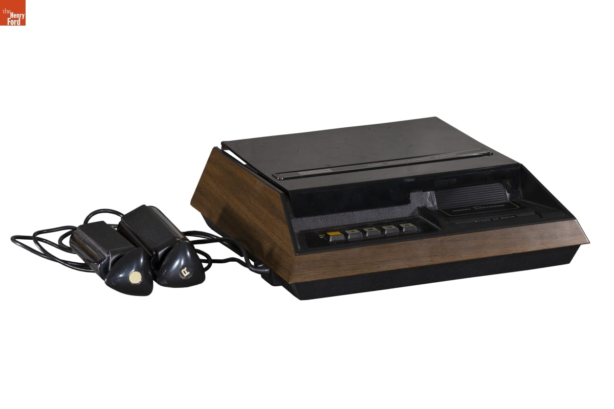 Fairchild Channel F Video Game System, 1976 Boxy brown-and-black gaming console with two stick-shaped controllers