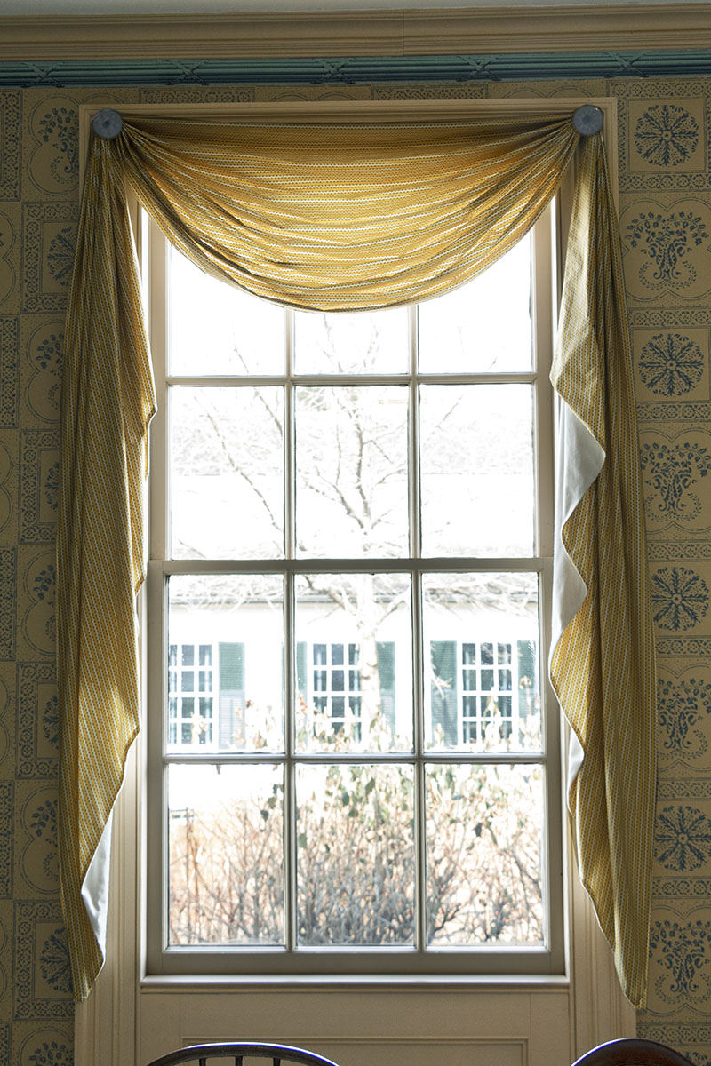 Window with curtains surrounded by wallpapered wall