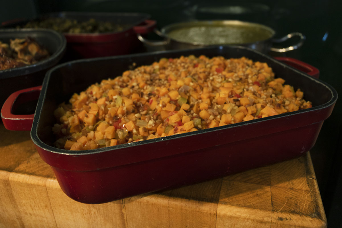 Sweet Potato Hash Red dish filled with a vegetable medley; other dishes visible in background