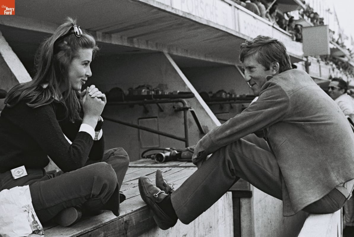Jochen Rindt and Nina Rindt Before the 24 Heures du Mans (24 Hours of Le Mans) Race, June 1967 Woman sitting cross-legged smiling at man sitting on low wall with feet extended, also smiling