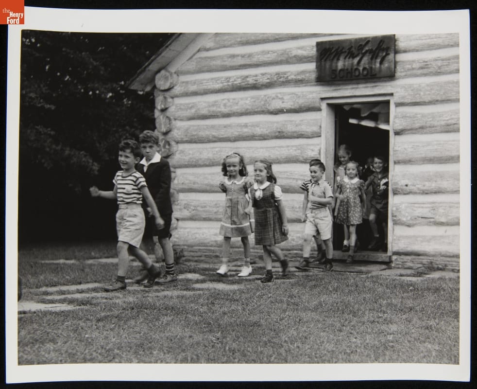 Edison Institute Schoolchildren Exiting McGuffey School, Greenfield Village, 1937-1940 Group of children walk out of a log cabin door