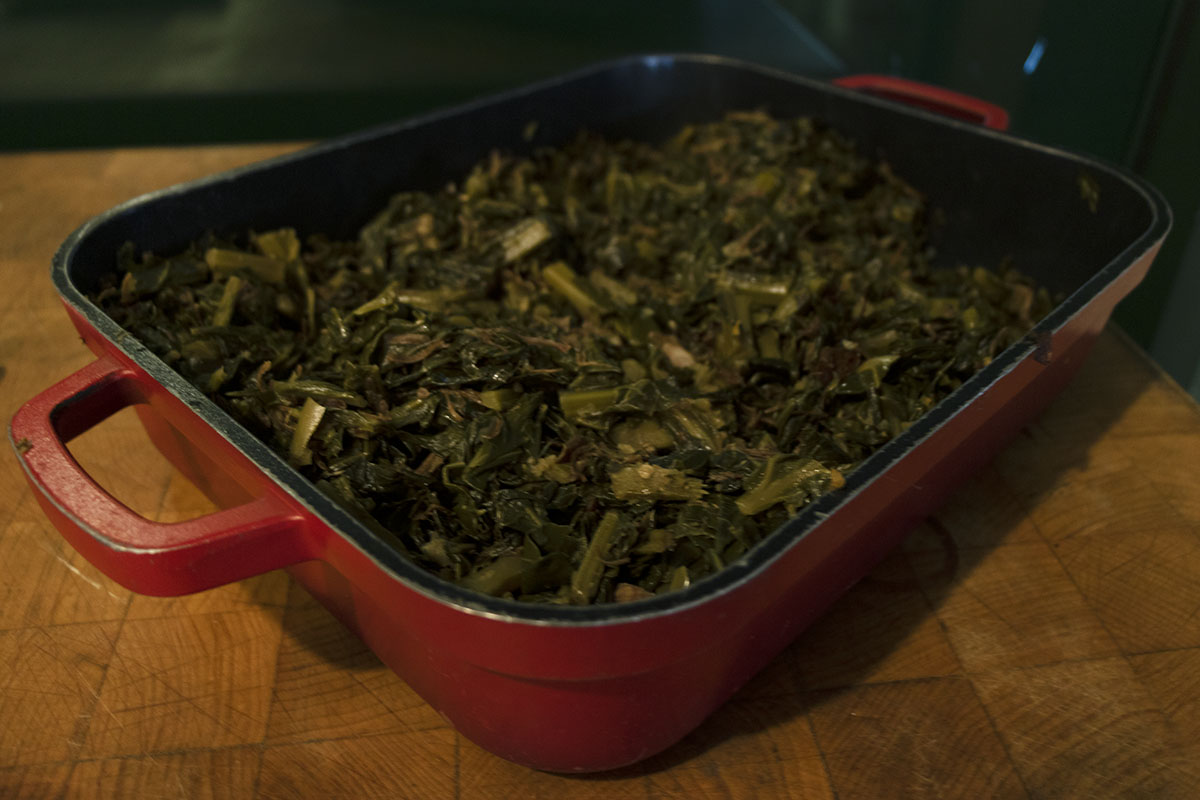 Collard Greens with Smoked Turkey, from A Taste of History in Greenfield Village Red casserole dish filled with cooked greens, sitting on butcher block