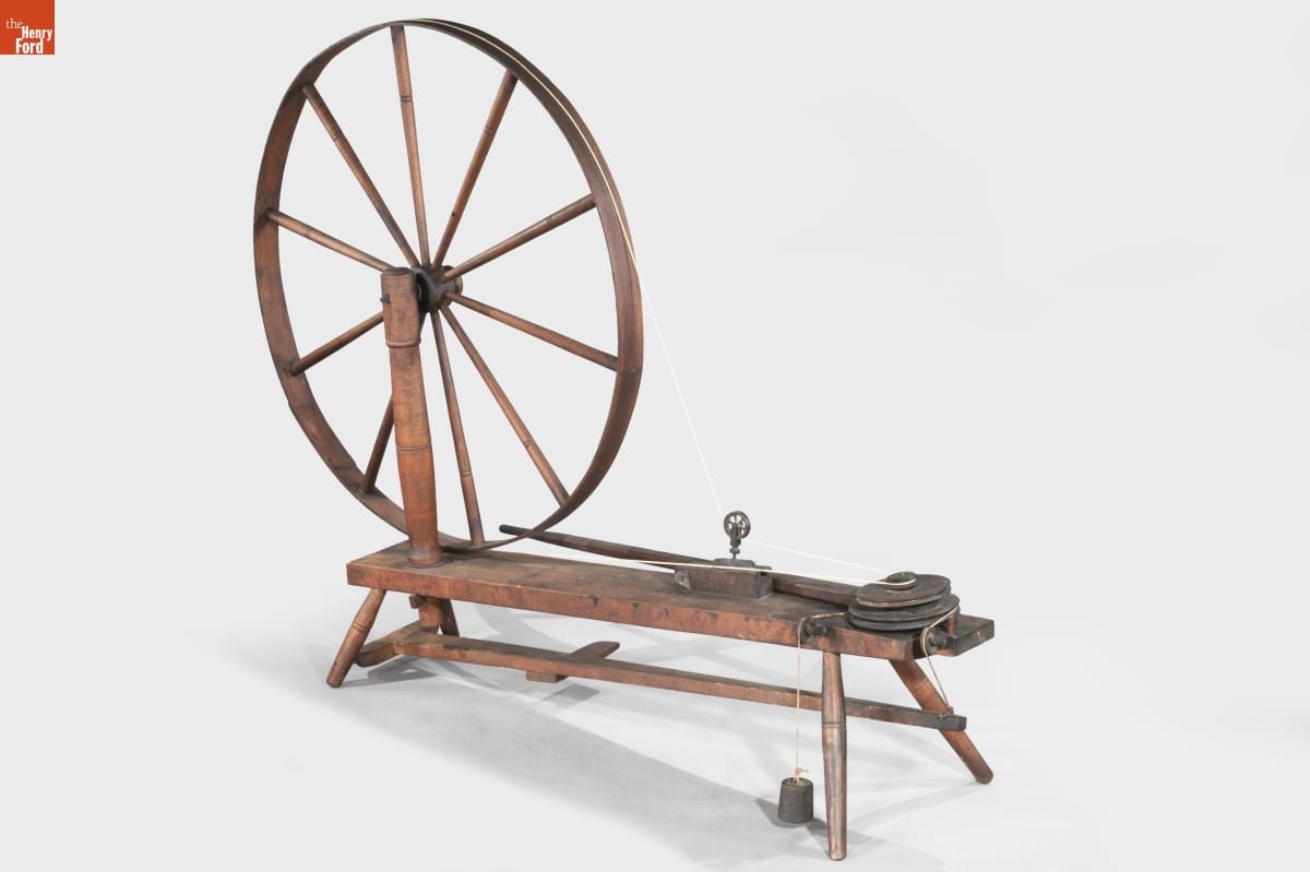 Wooden spinning wheel with a large wheel and flat bench-like area