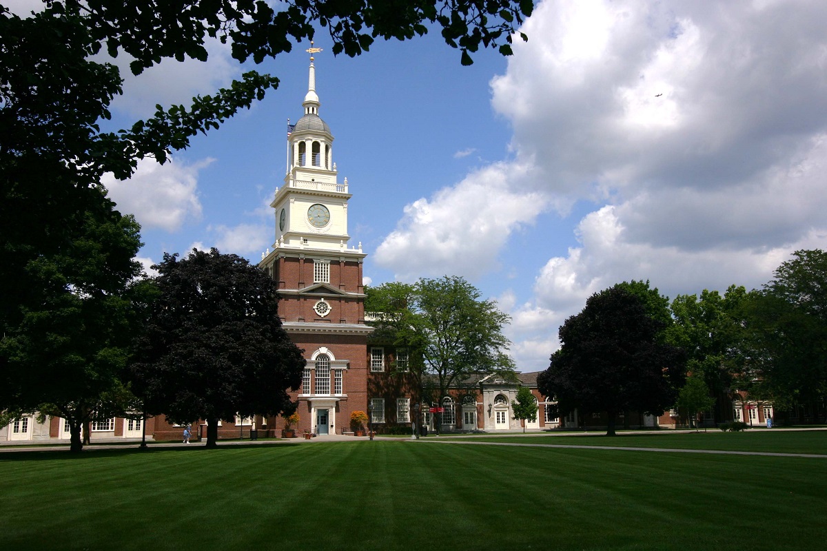 Clocktower entrance to Henry Ford Museum Brick building with tall clocktower, seen across a large grass lawn with a few trees