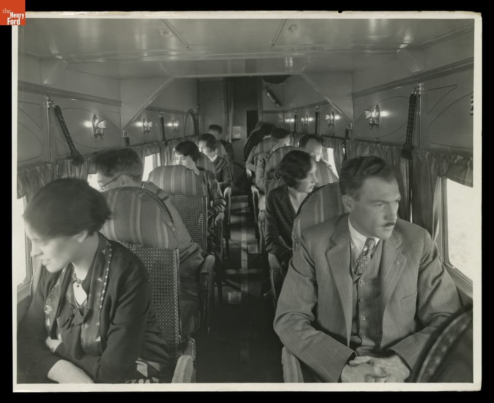 Passengers aboard Ford Tri-Motor Airplane, 1929 Passengers sit, one on either side of the aisle, looking out the windows of an airplane